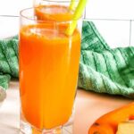 A picture of a glass of carrot juice with turmeric, ginger and orange.