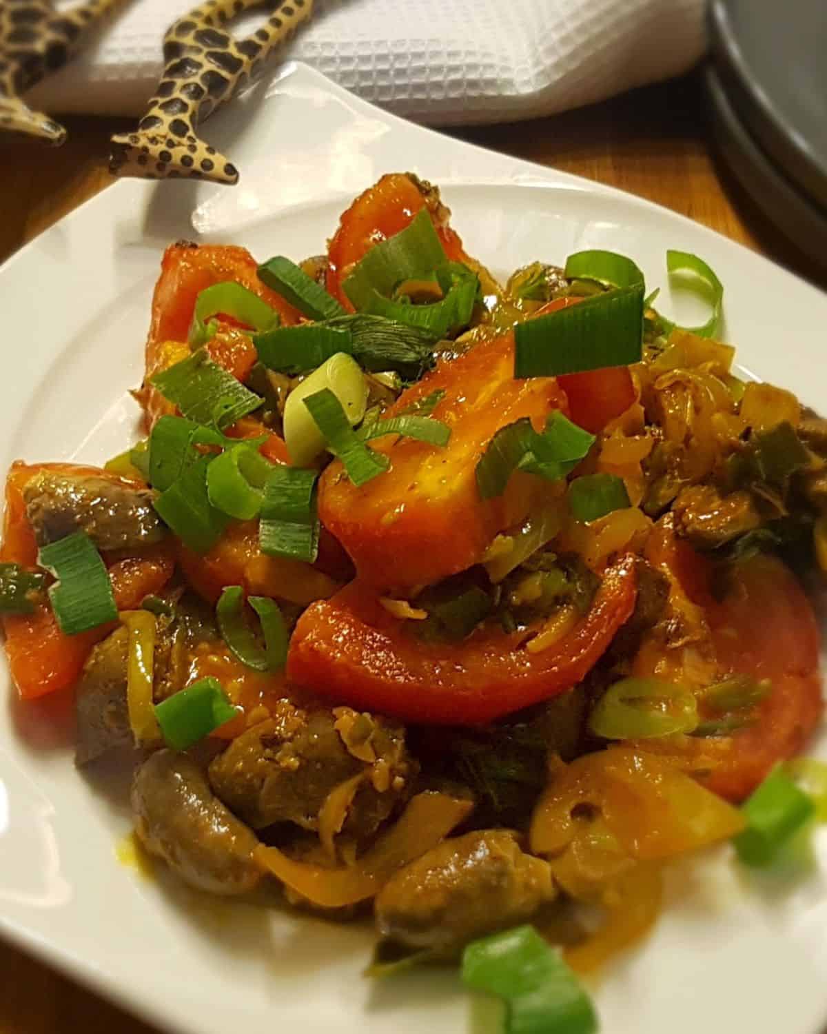 Sauteed chicken hearts served on a plate and garnished with scallions.