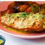 Chicken served on a plate with some tomato sauce and a side of honey mustard dressing.