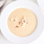 Instant Pot Potato Leek Soup in a bowl, garnished with leek and bacon