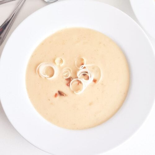 Instant Pot Potato Leek Soup in a bowl, garnished with leek and bacon