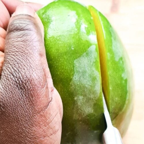 cutting a mango with a knife for eating