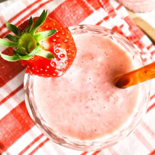 A zoomed in picture showing a glass of strawberry and banana smoothie.