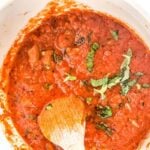 Marinara sauce garnished with some basil leaves.