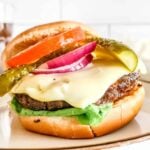 A picture of a hamburger served on a bun with toppings.