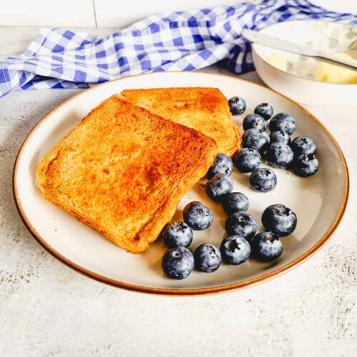 A picture of toasted bread and some blueberries on a plate.