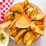 An overhead picture of potato wedges and a cheese dip.