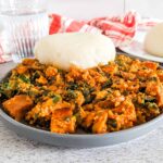 Vegan egusi soup and fufu served on a plate.