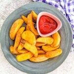 An overhead picture of potato wedges and some ketchup.