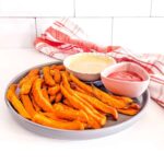 Air fryer sweet potato fries on a plate with some dipping sauces.