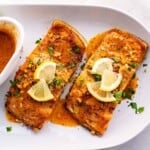 Air fried frozen salmon on a plate garnished with lemon.