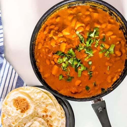 Butterbean curry in a cooking pan with a side of rotis.