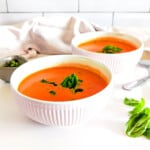 Homemade tomato soup in bowls, garnished with basil.