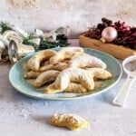 A plate of Vanillekipferl cookies with some Christmas decoration in the background.
