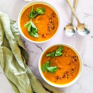 Two bowls of spicy carrot and coriander soup.
