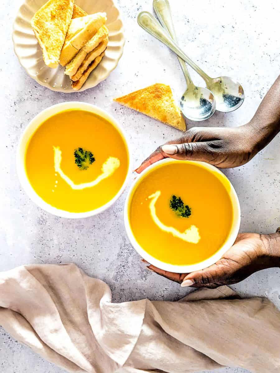 An overhead picture of bowls of pumpkin soup and some toasted bread.