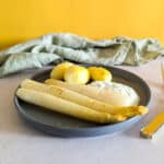 A plate of white asparagus with potatoes, and a yogurt dip.