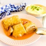 Plated sarma cabbage rolls alongside some mashed potatoes.