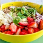 Strawberry, goat cheese and avocado salad inside a yellow bowl.