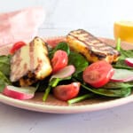 Air-fried halloumi served with tomatoes and salad greens on a plate.