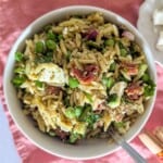 A square zoomed in image of orzo salad with feta, cucumber and peas in a bowl.