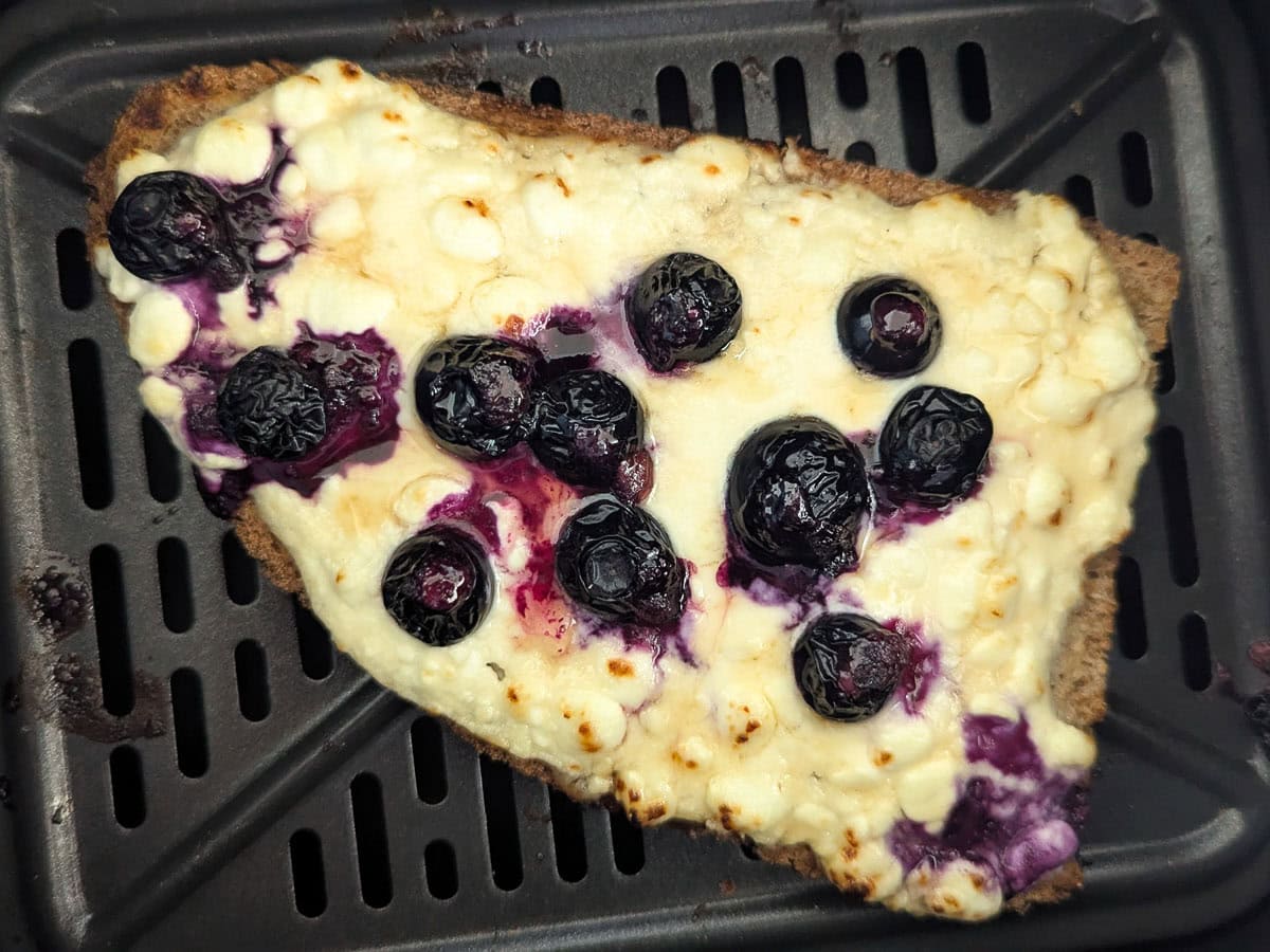 Air fryer blueberry cottage cheese toast inside an air fryer basket.