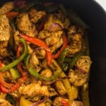 Air fried chicken fajita with bell peppers and onion cooked in an air fryer basket.