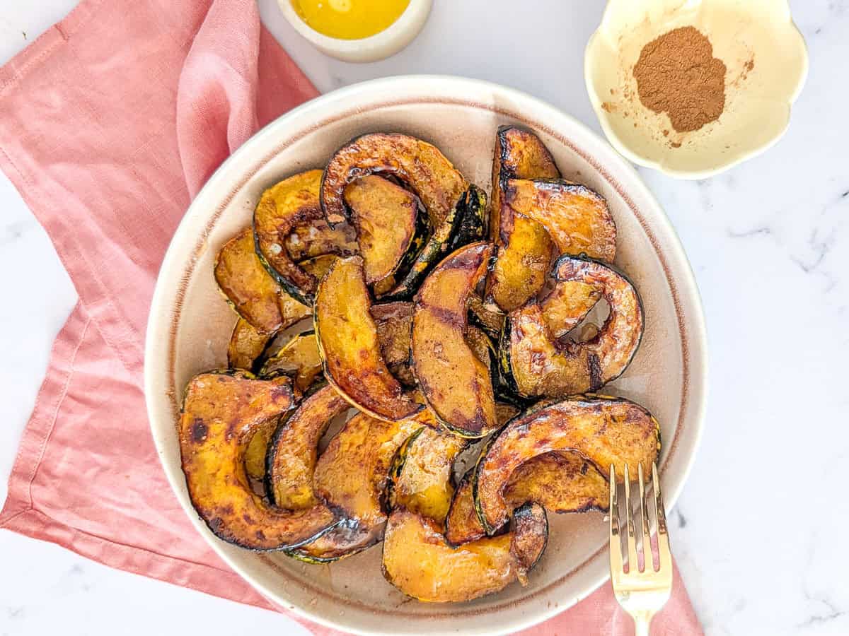 Horizontal photo of air fryer acorn squash slices served with cinnamon and butter.