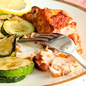 Air fryer salmon served on a plate with some zucchini.