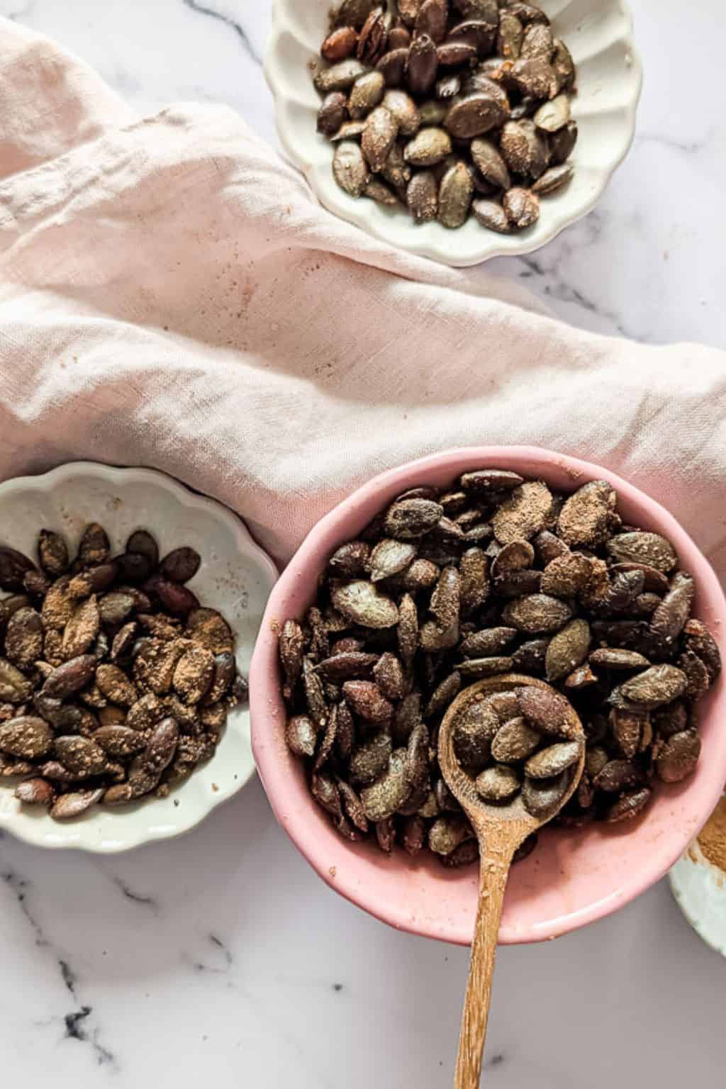 A top-down picture of three bowls of roasted pumpkin seeds.
