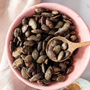 Bowl of air fryer pumpkin seeds coated with cinnamon sugar.