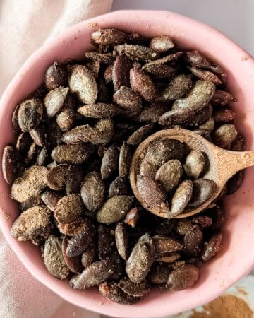 Bowl of air fryer pumpkin seeds coated with cinnamon sugar.