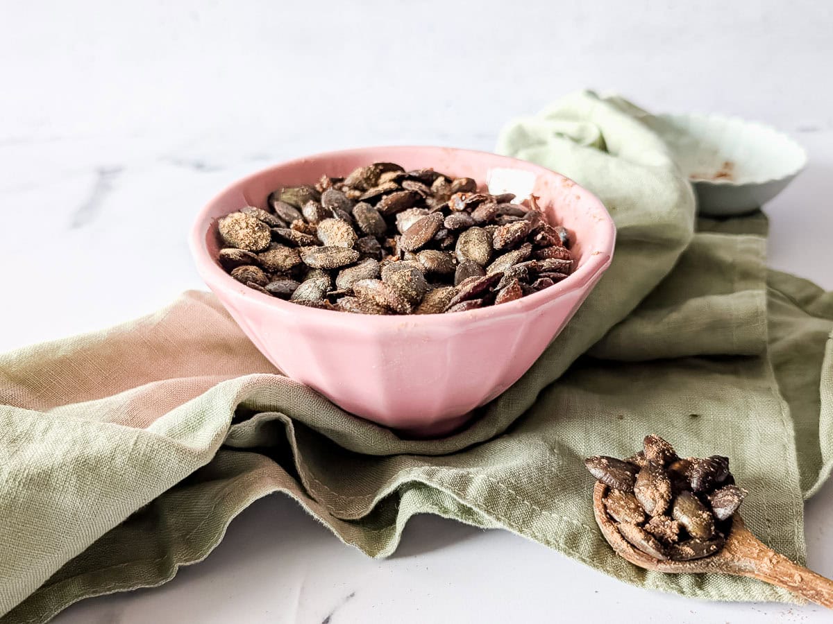 A horizontal image of air fryer pumpkin seeds in a pink bowl.