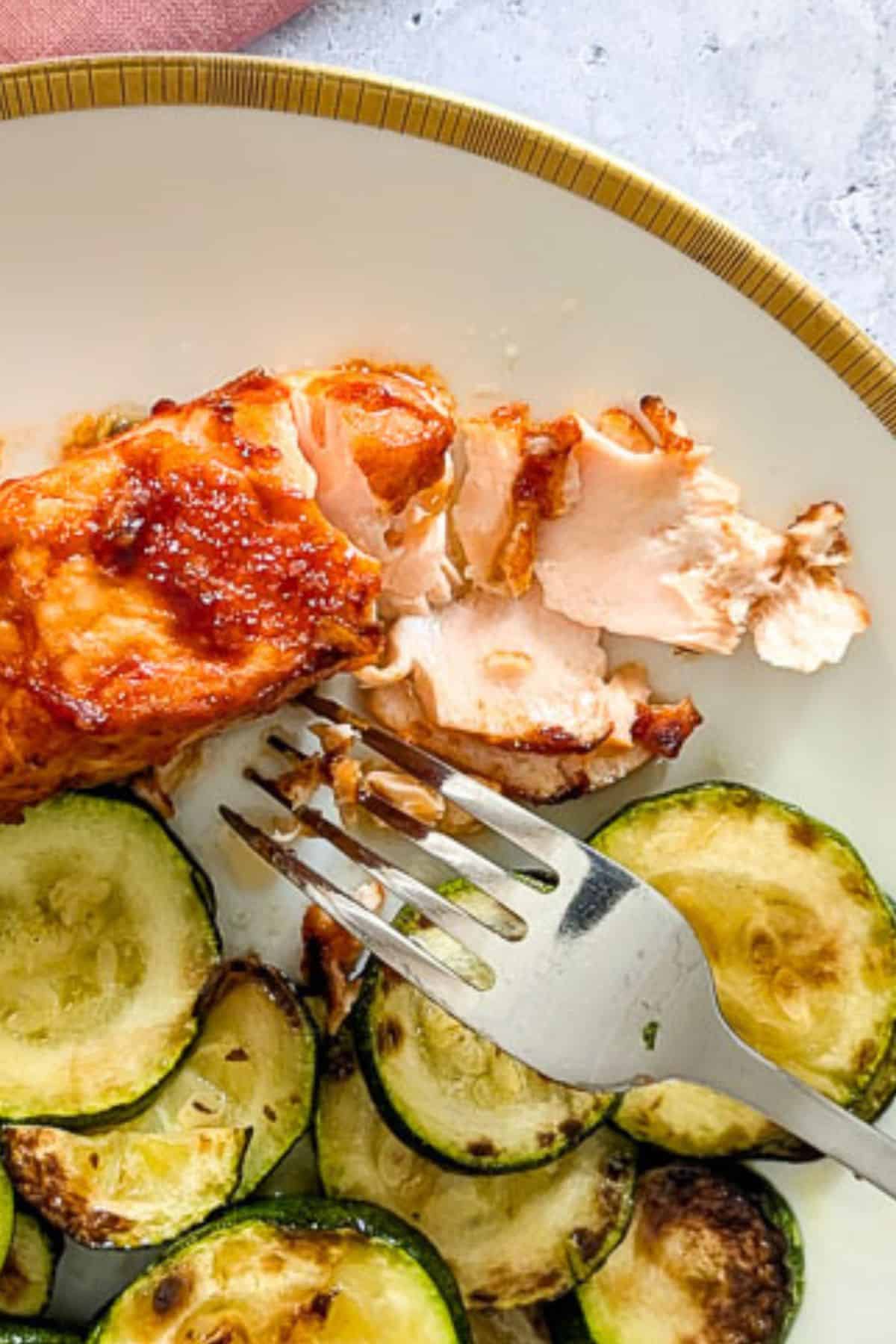 A zoomed-in vertical image of air fryer salmon served on a plate.