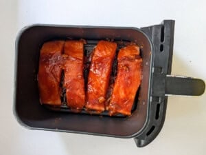 This image shows marinated air fryer salmon inside an air fryer basket.