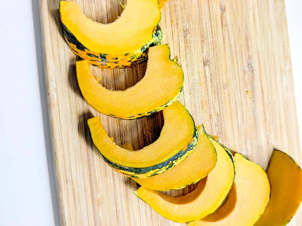 Raw squash slices on a wooden cutting board.