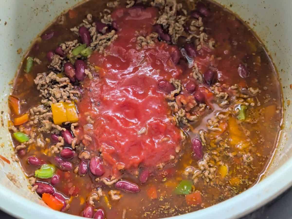 Chili mixture with kidney beans, vegetables, and crushed tomatoes in a pressure cooker.