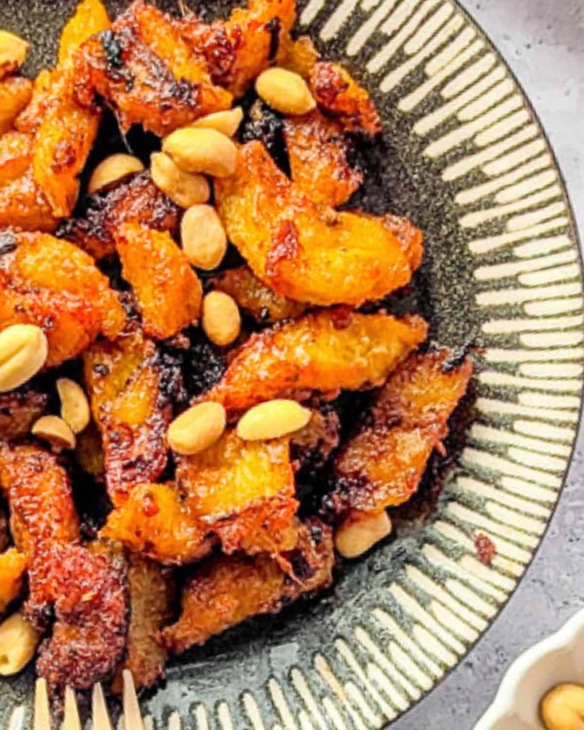 a zoomed in image of kelewele served with peanuts on a plate.