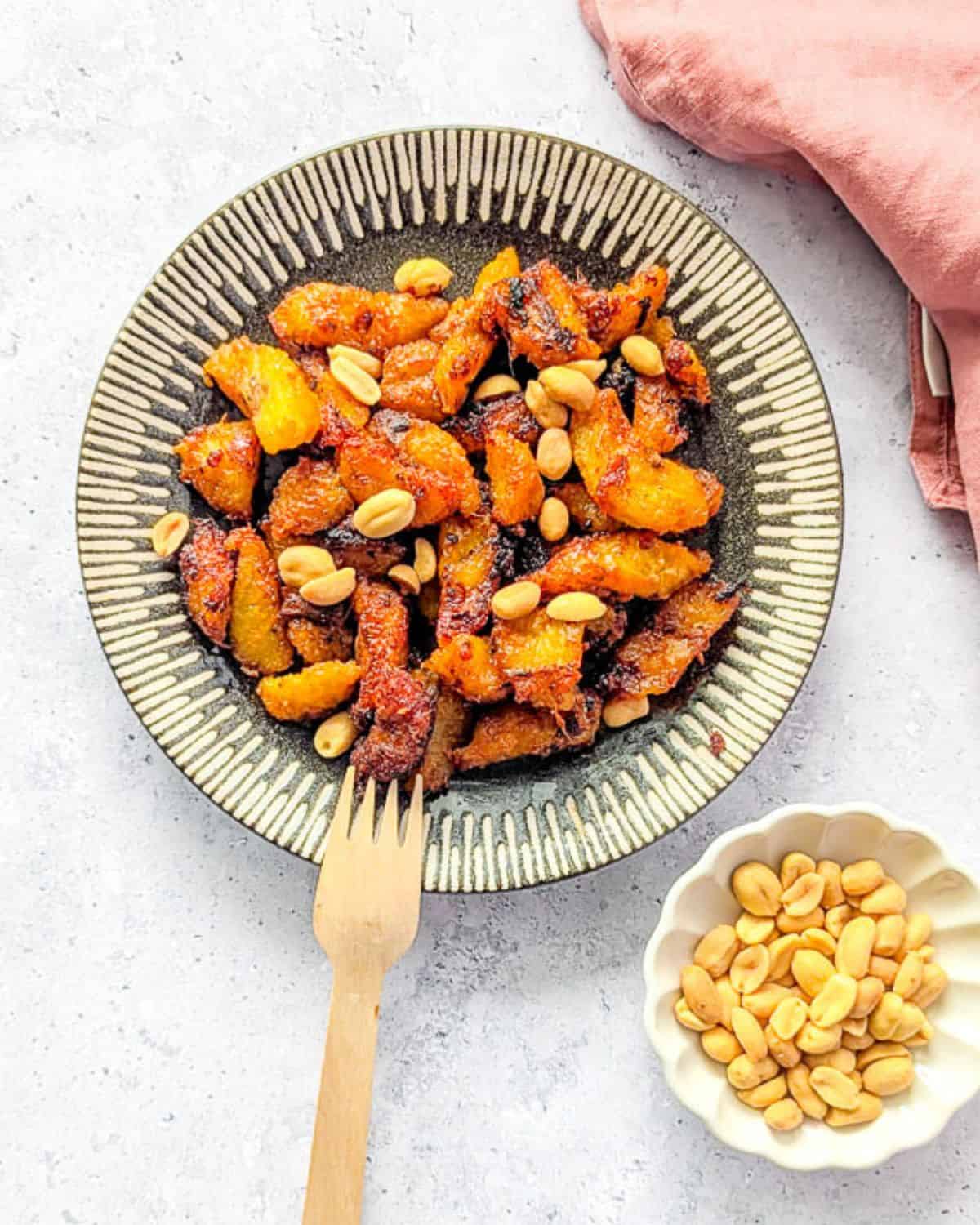 Kelewele served on a patterned plate with roasted groundnuts.