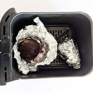 Whole roasted beets wrapped in foil inside an air fryer.