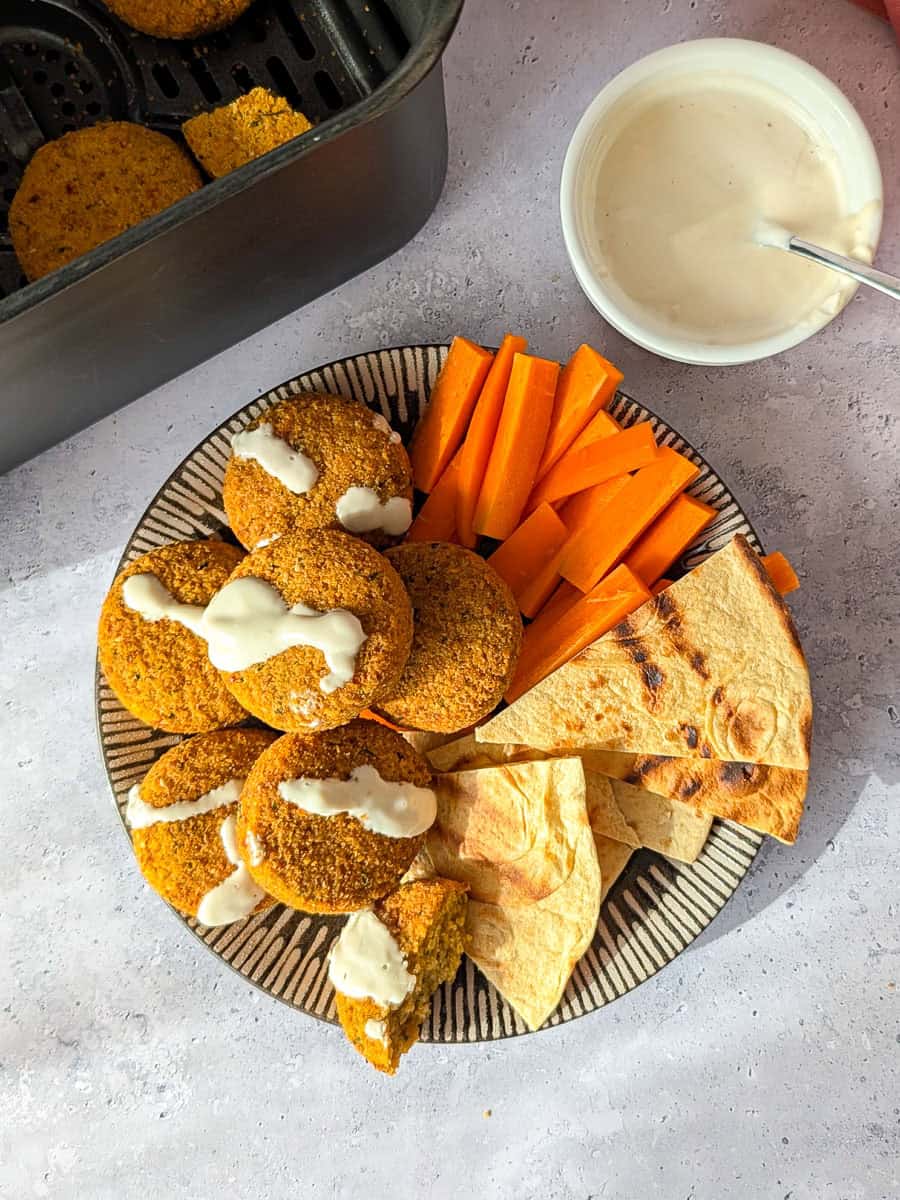 Falafel served with carrot sticks, pita, and yogurt tahini sauce.