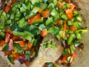 Peppers and other vegetables cooking in a pot.