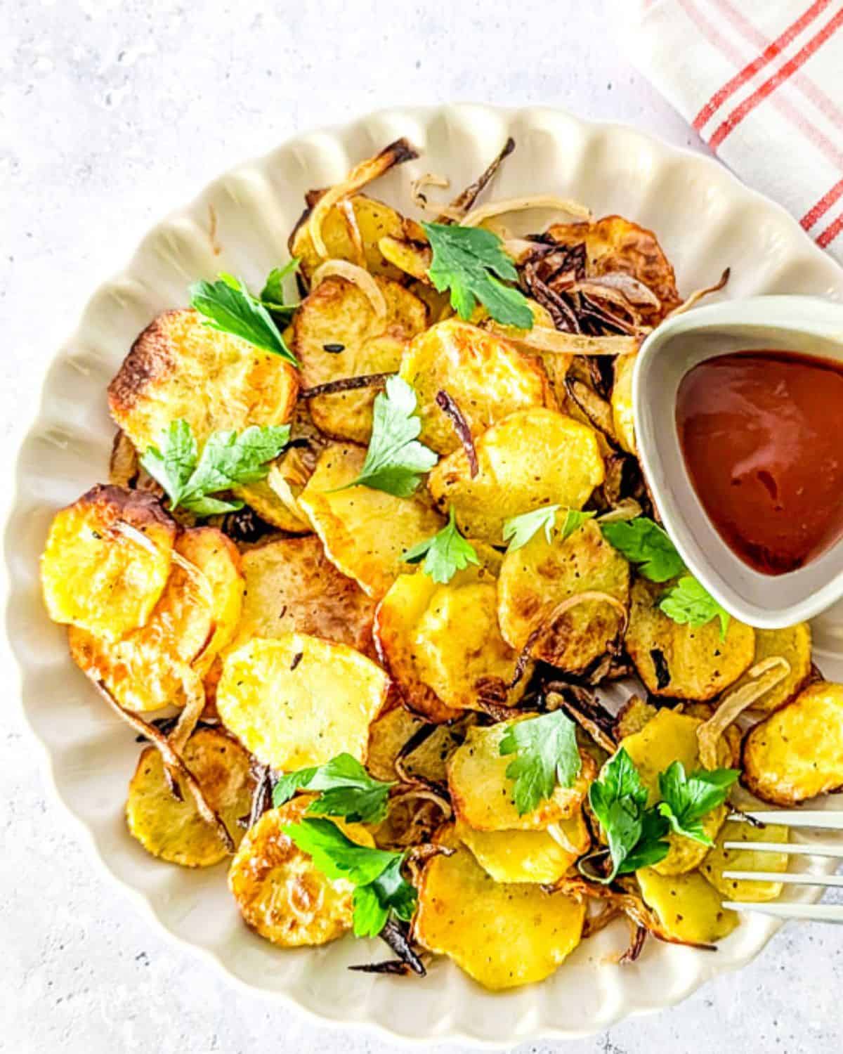 A close up photo of air fryer sliced potatoes with onions and parsley.