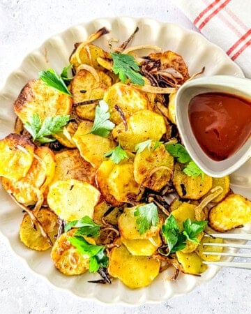 Air fried sliced potatoes and onions served with ketchup and parsley.
