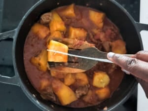 Using a knife to check cooked matoke for doneness.