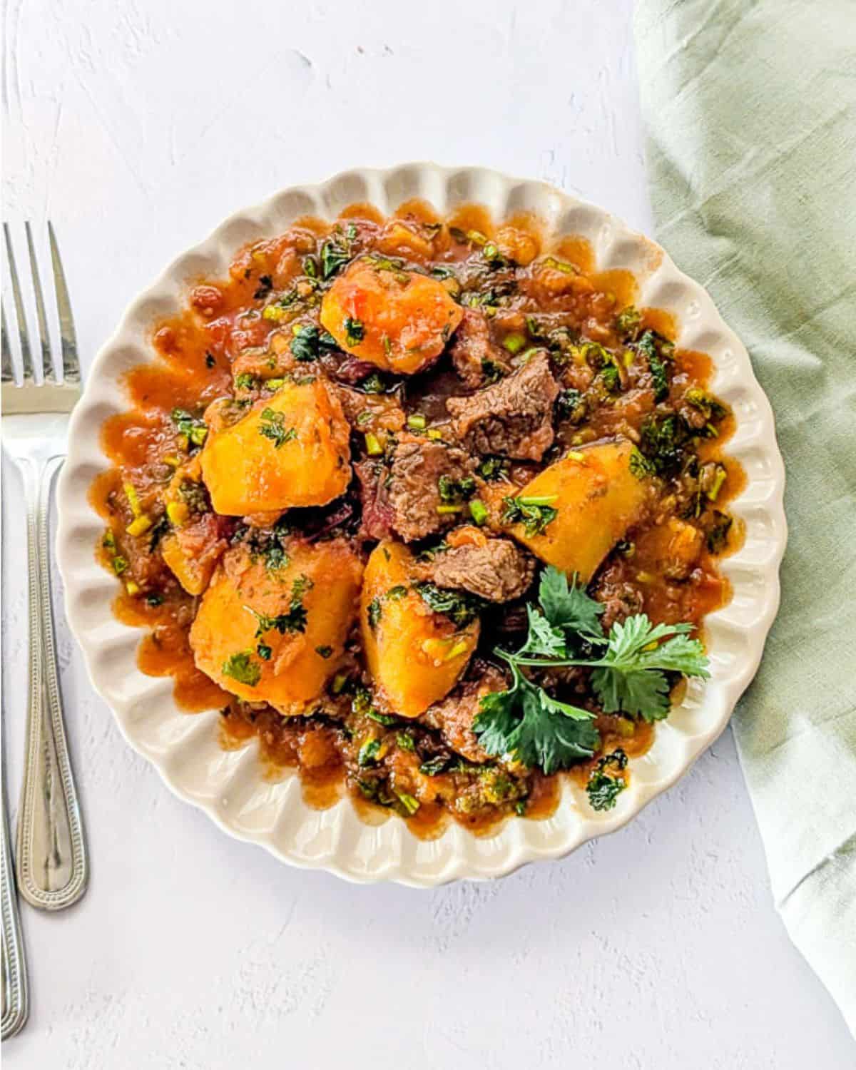 Top-down vertical image of matoke and beef stew on a plate.