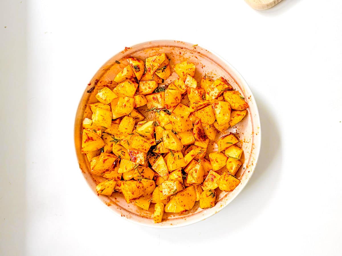 Diced and seasoned potatoes in a bowl.